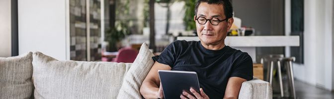 man sitting on couch using a tablet