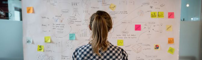 Woman looking at board covered in sticky notes