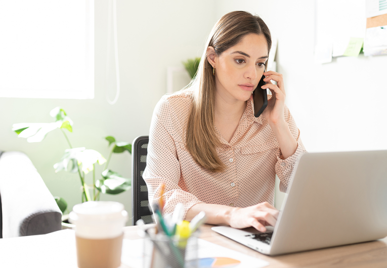 Businesswoman talking to a client on her phone and looking serious and worried while working in her office