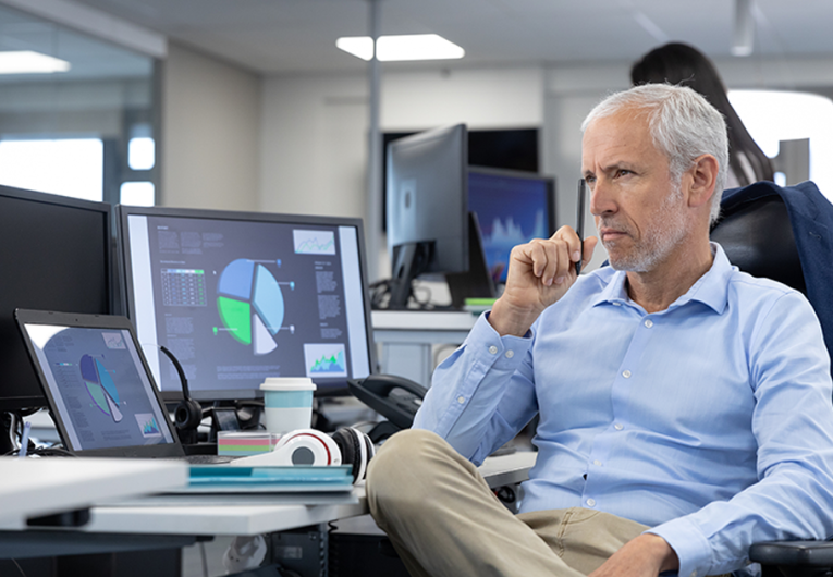 businessman working in a modern office, sitting at desk using computers, thinking.