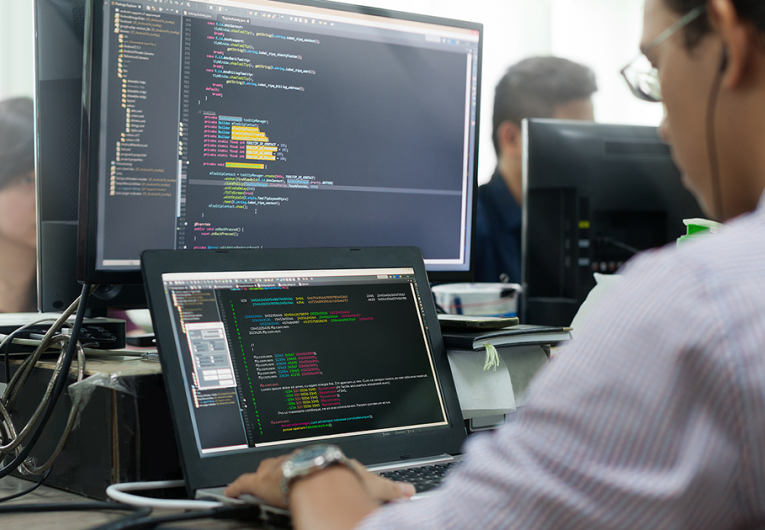 Developer Looking at Screen Sitting at Desk Working on Desktop Computer