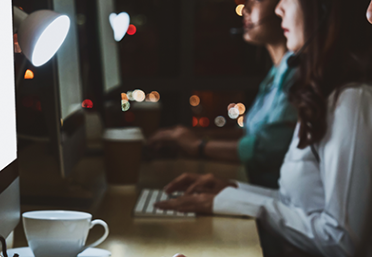 Employee working in front of computer at desk during night shift. 