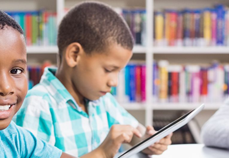 elementary school children in library using tablets and laptops on WiFi