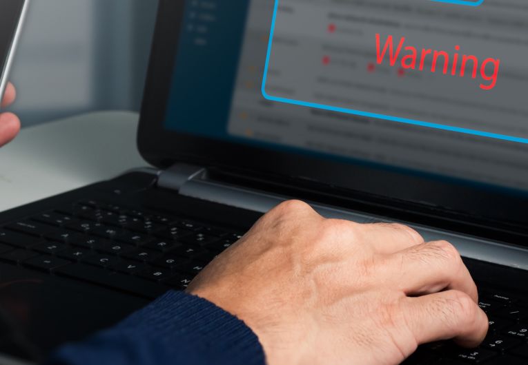 Person's hands with phone and laptop with secuirty pop up 