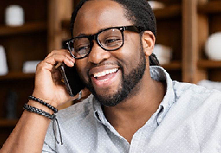 A successful and confident entrepreneur is smiling as he speaks to someone on a mobile phone.