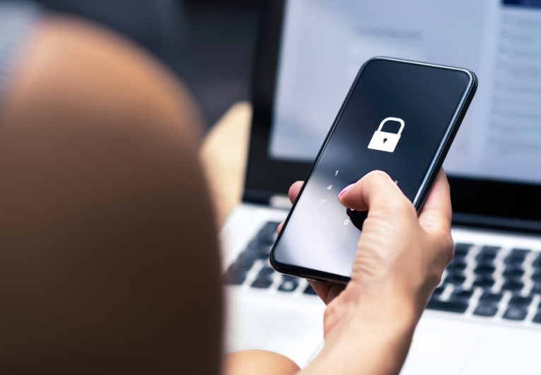 Female holding phone with security lock  in front of computer screen