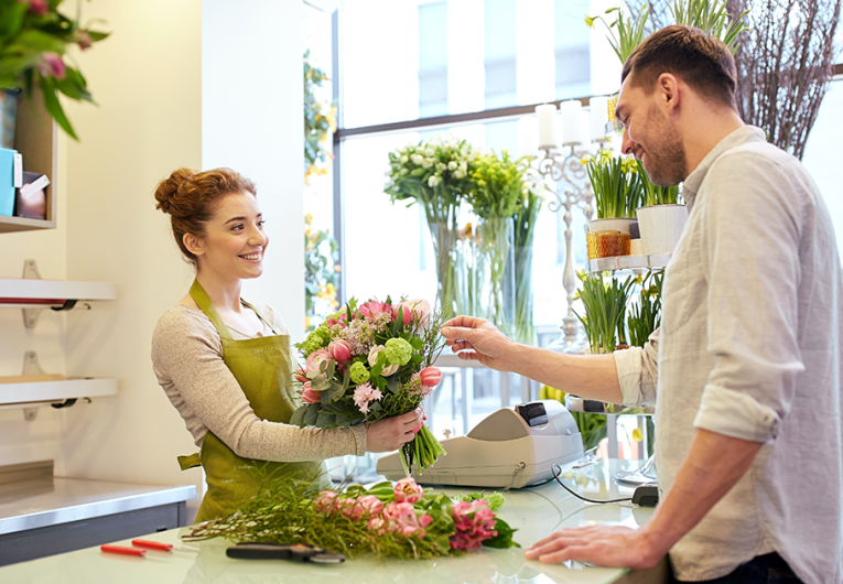 happy smiling florist woman making bouquet for and male customer at flower shop