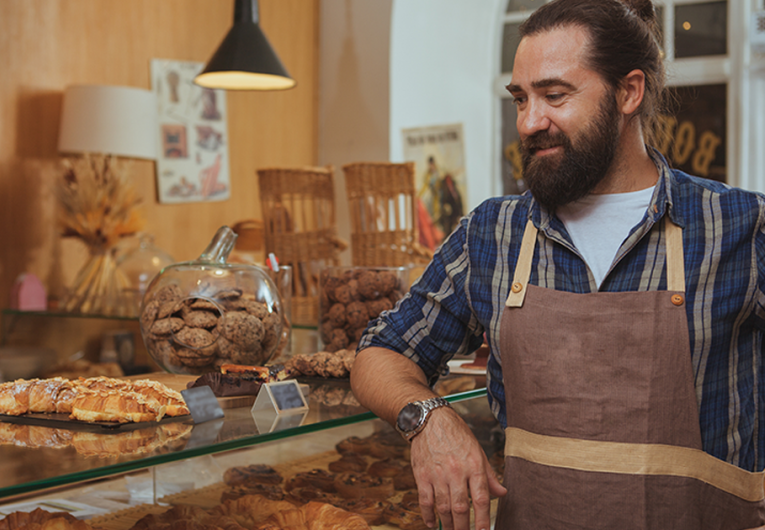Bearded baker enjoying working at his own bakery shop.