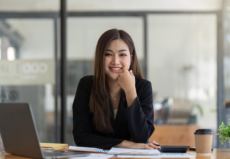 Young businesswoman working at desk smiling with computer laptop on desk. 