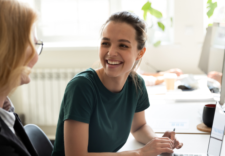 Happy smiling female trainee discussing business ideas with adult trainer