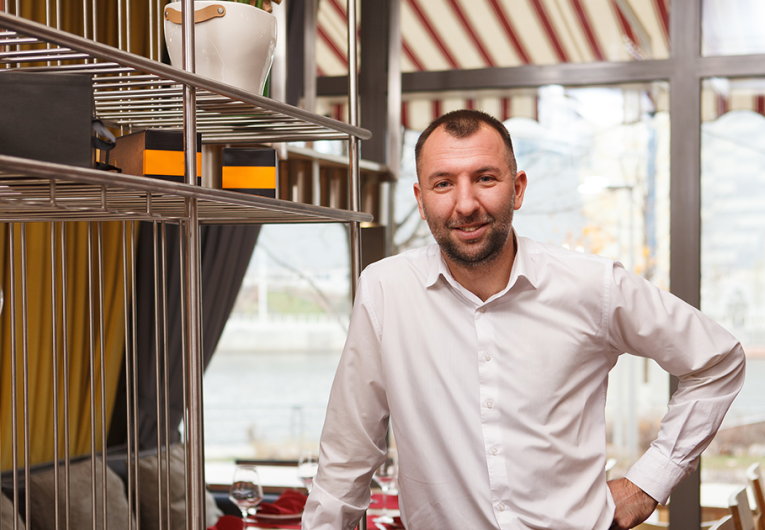 Cheerful friendly male waiter welcoming you at the restaurant