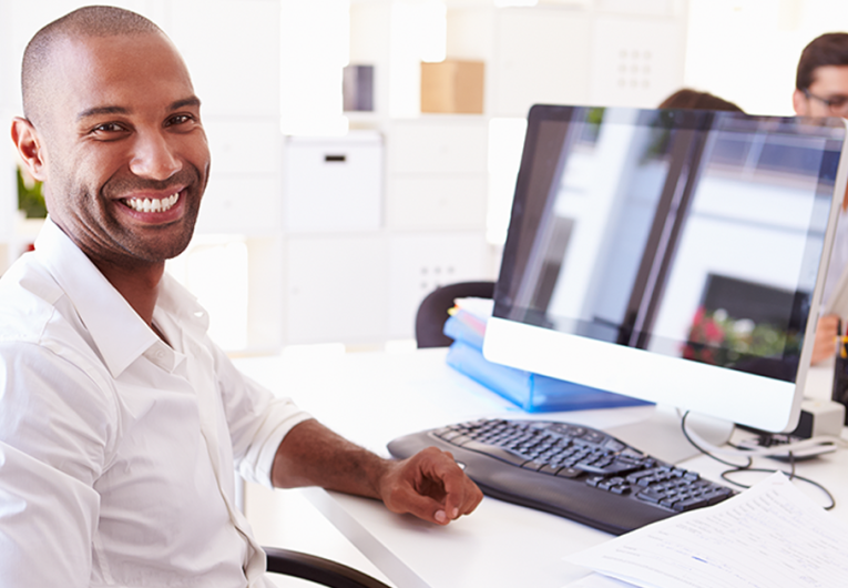 Businessman At Computer In Office smiling
