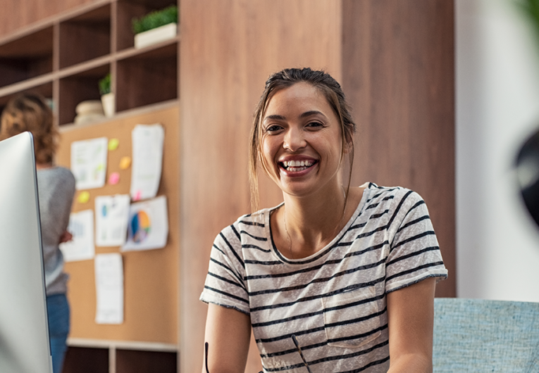 Portrait of smiling young business woman sitting at her desk in an office.