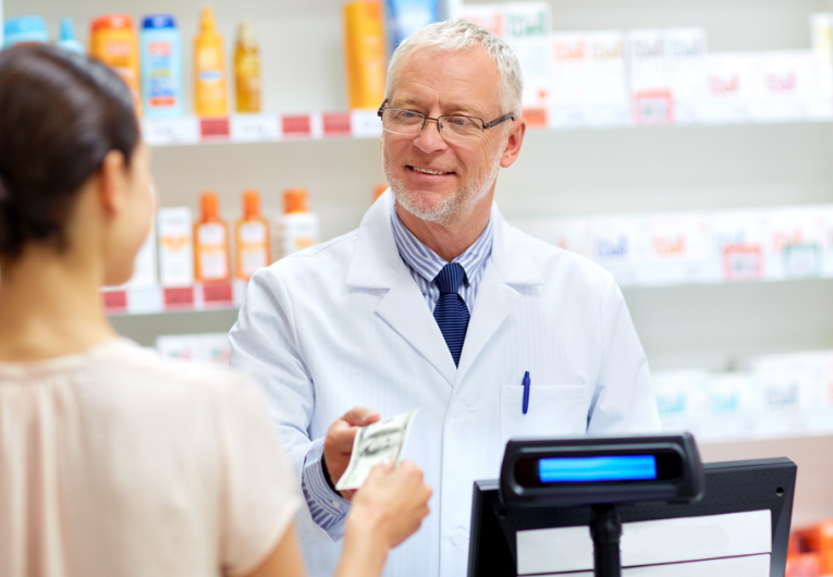 female customer paying money to senior pharmacist at pharmacy cash register
