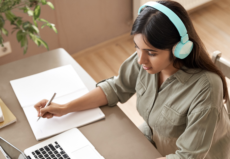 Young entrepreneur wearing headphones taking notes 