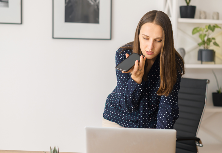 Busy female employee is using voice assistant on the smartphone
