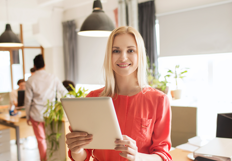 happy businesswoman in office with tablet
