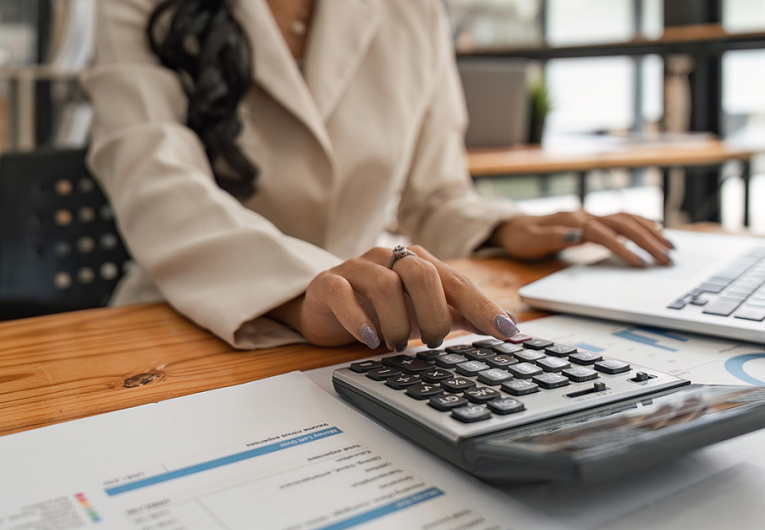 Close-up of businesswoman hands using a calculator to check company finances and earnings and budget