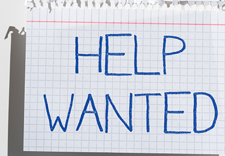 A piece of notebook paper with "Help Wanted" written on it. 