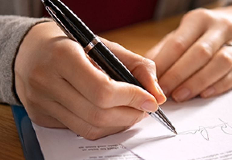 Closeup of the hands of a business person holding a pen while reviewing a document.