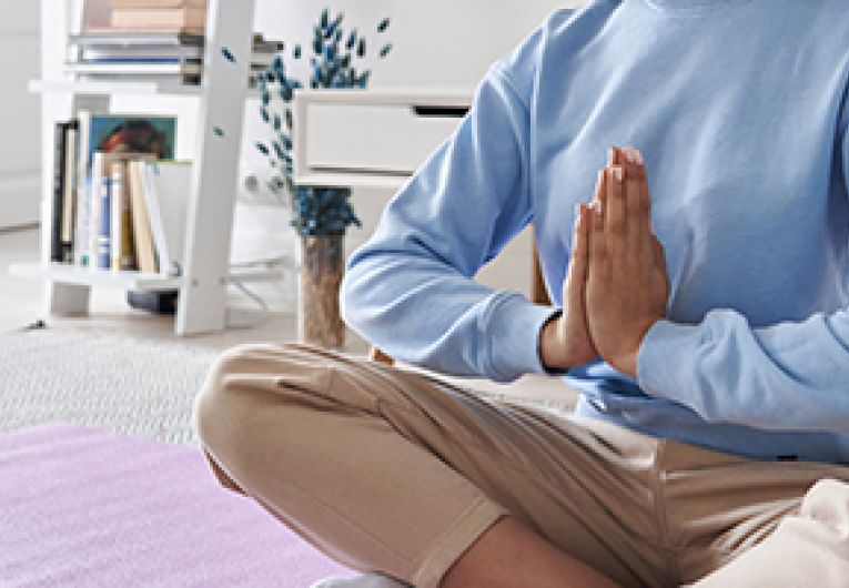 A person meditating on a yoga mat.
