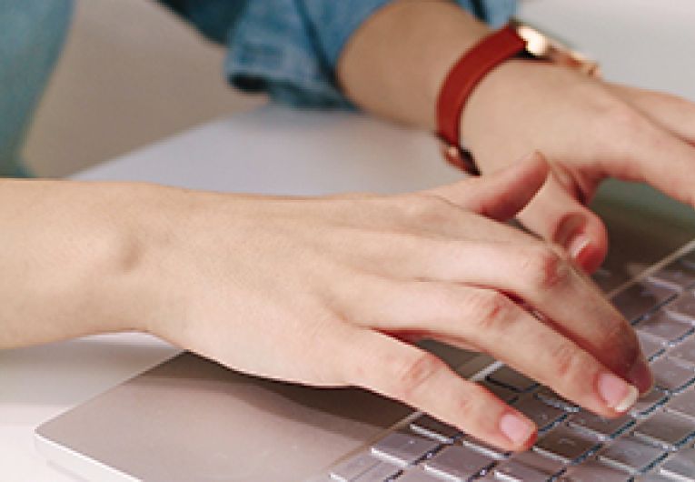 Image of hands typing on a laptop.