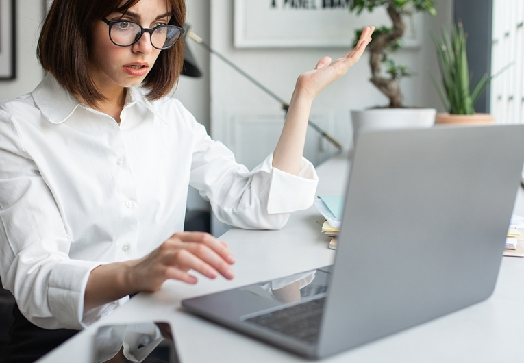 Shocked businesswoman looking at laptop with disbelief, working in coworking space, office.