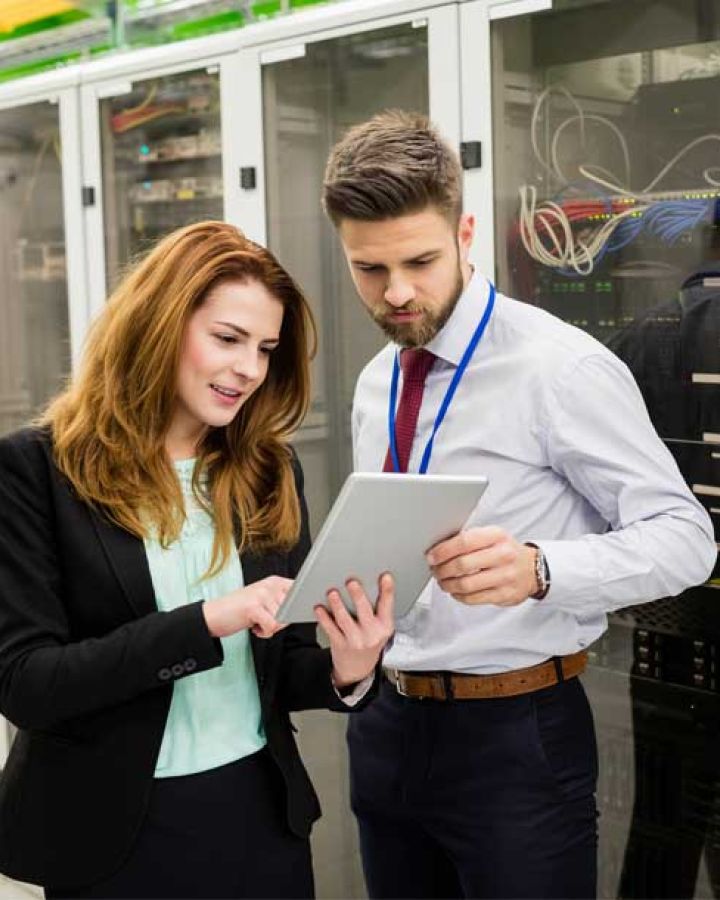 man and woman looking at tablet in front of network rack