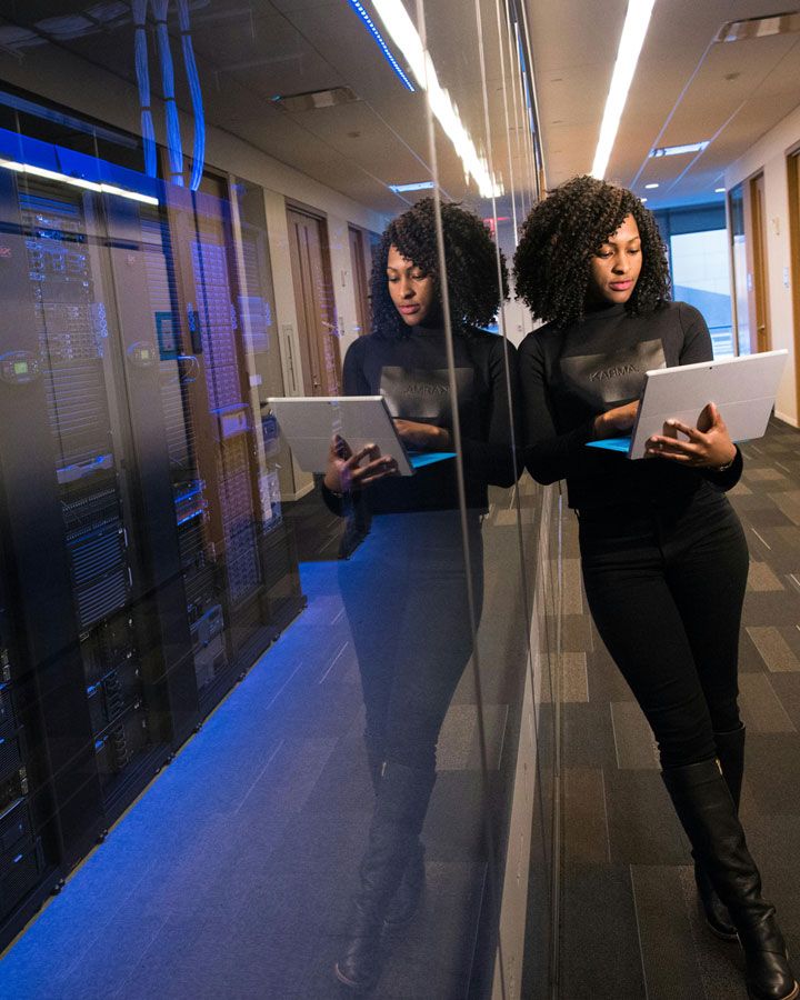 Woman leaning on a  glass wall in front of a row of servers