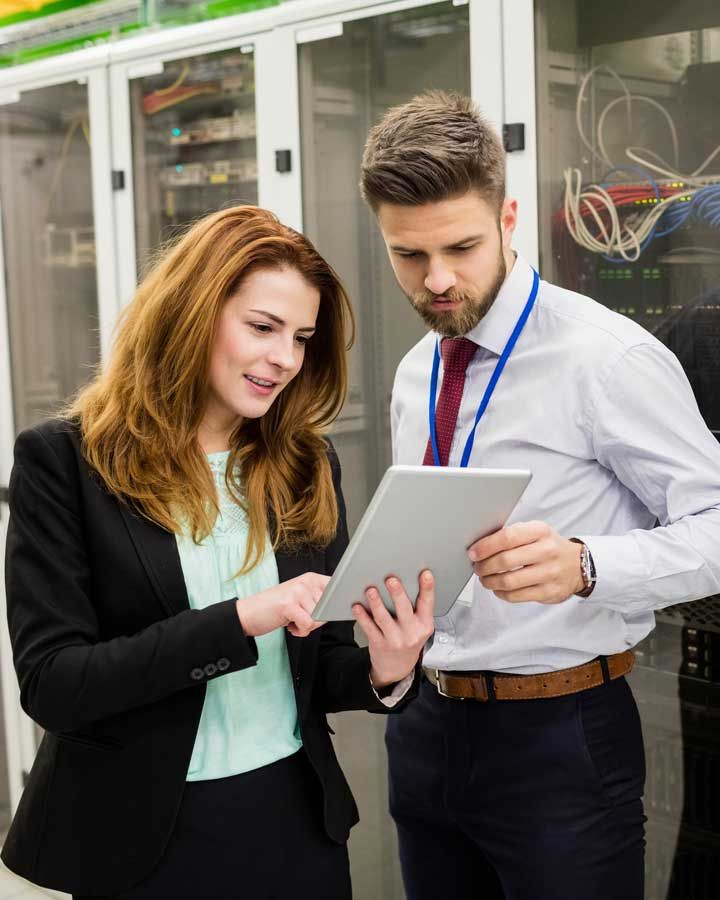 Man and woman looking at tablet in server room