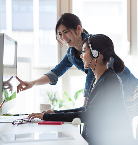 two women discussing something on the computer