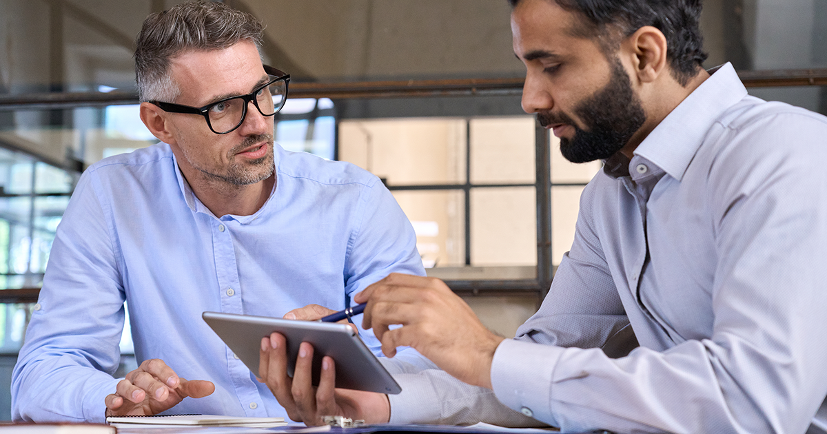Two businessmen discussing financial report planning sitting at table in office.