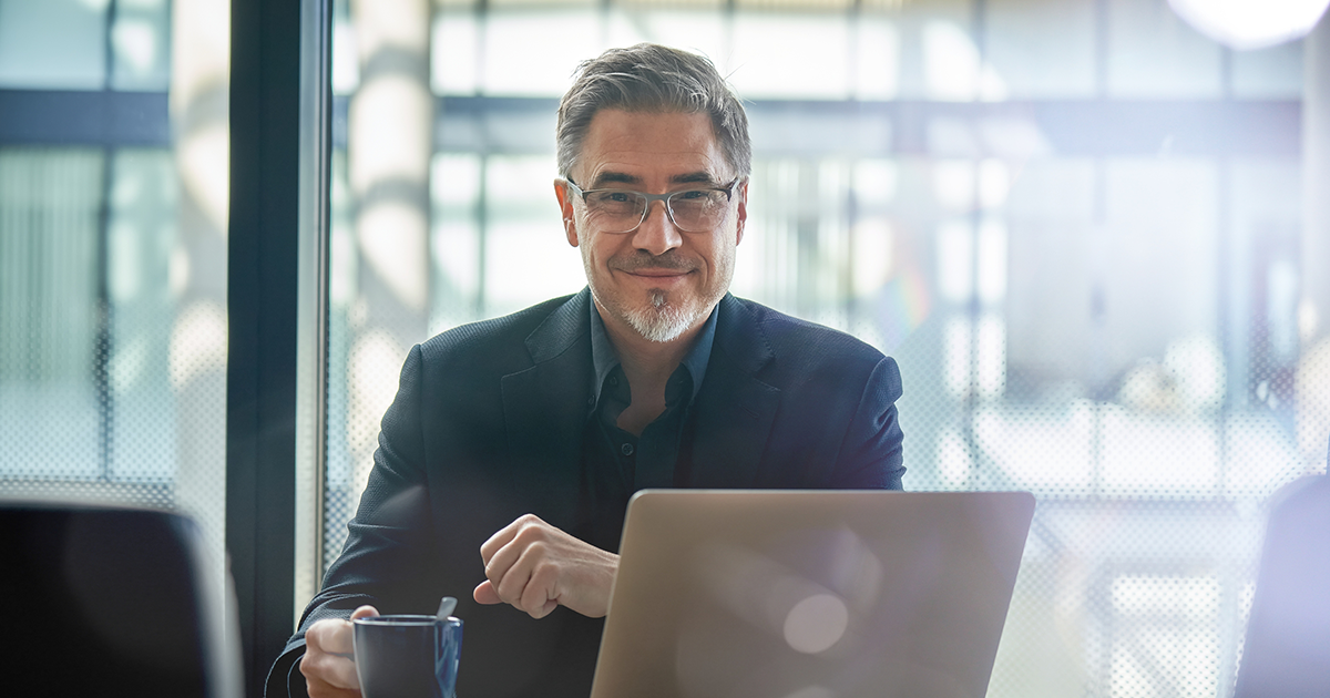 Mature businessman sitting in in office working with laptop computer.