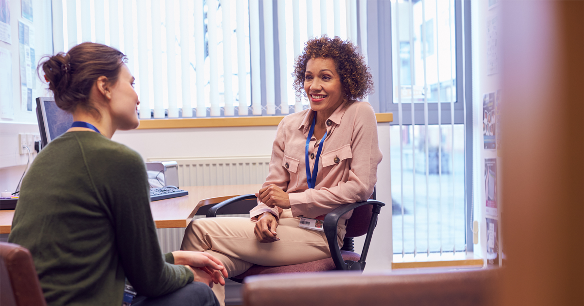 Female business manager having a conversation with female employee sitting down in office
