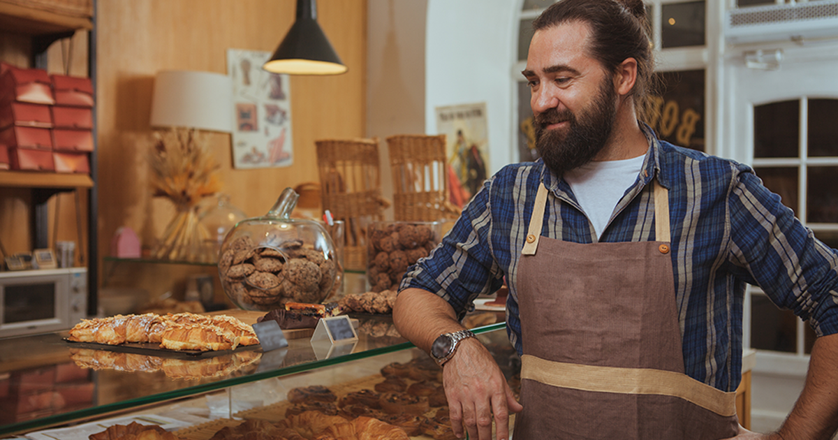 Bearded baker enjoying working at his own bakery shop.