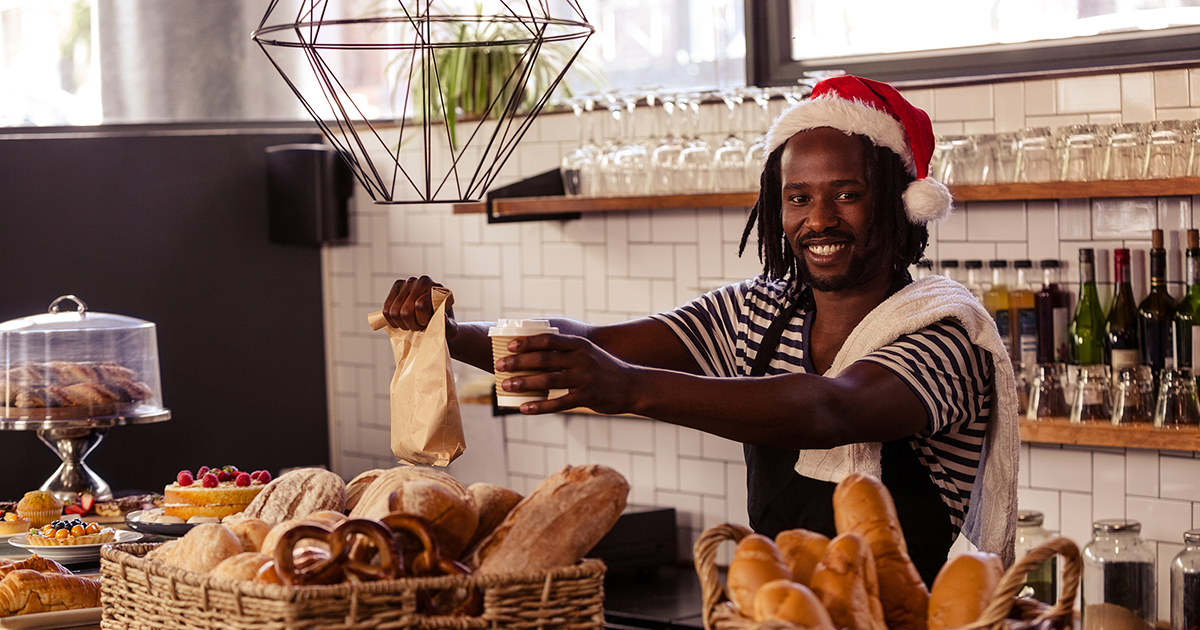 Smiling employee serving take away order at coffee shop