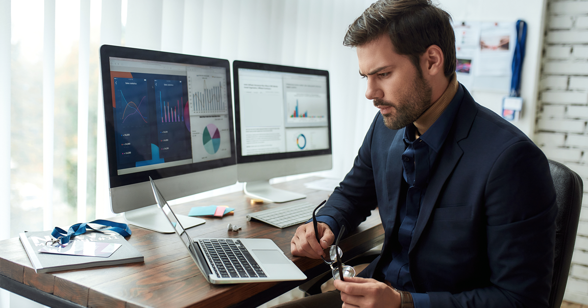Young focused businessman or financial analyst sitting at his workplace in the office and working on laptop. 