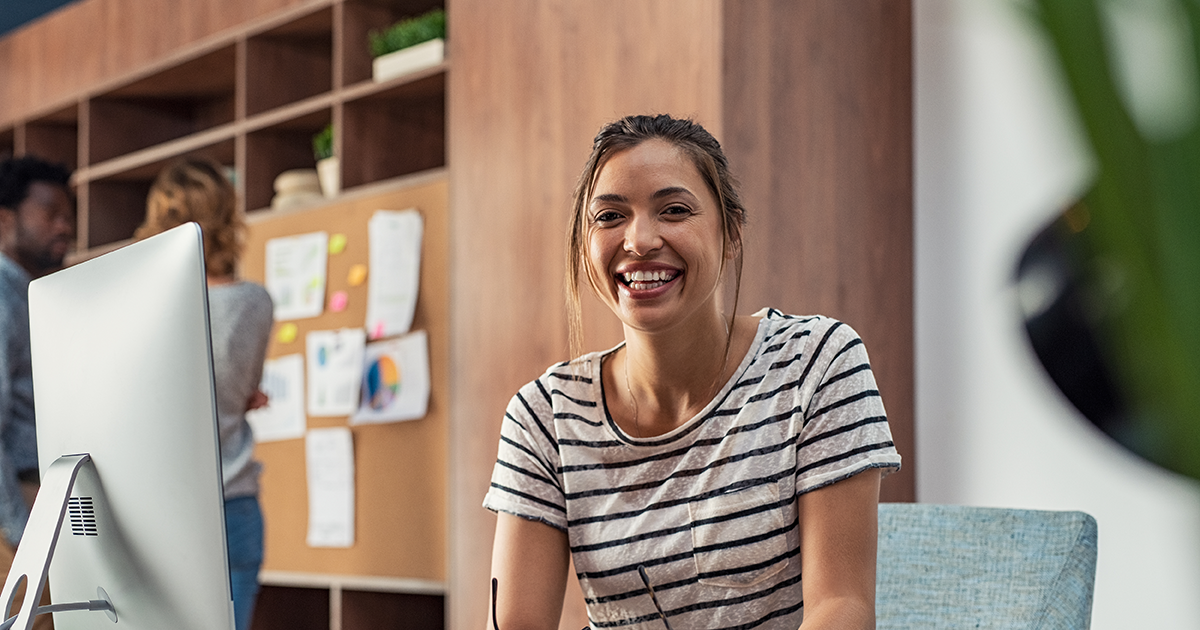 Portrait of smiling young business woman sitting at her desk in an office.