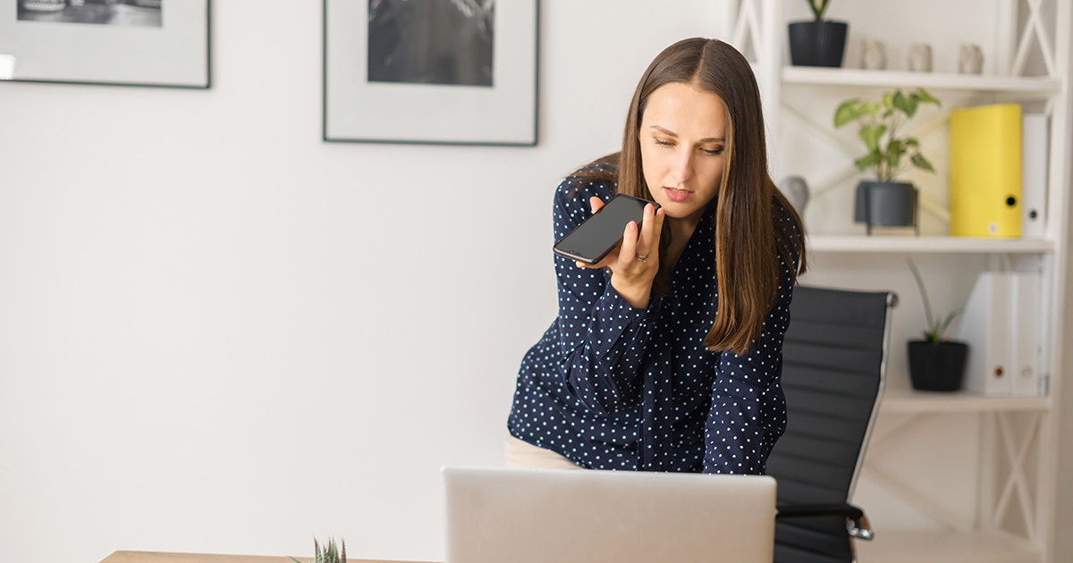Busy female employee is using voice assistant on the smartphone