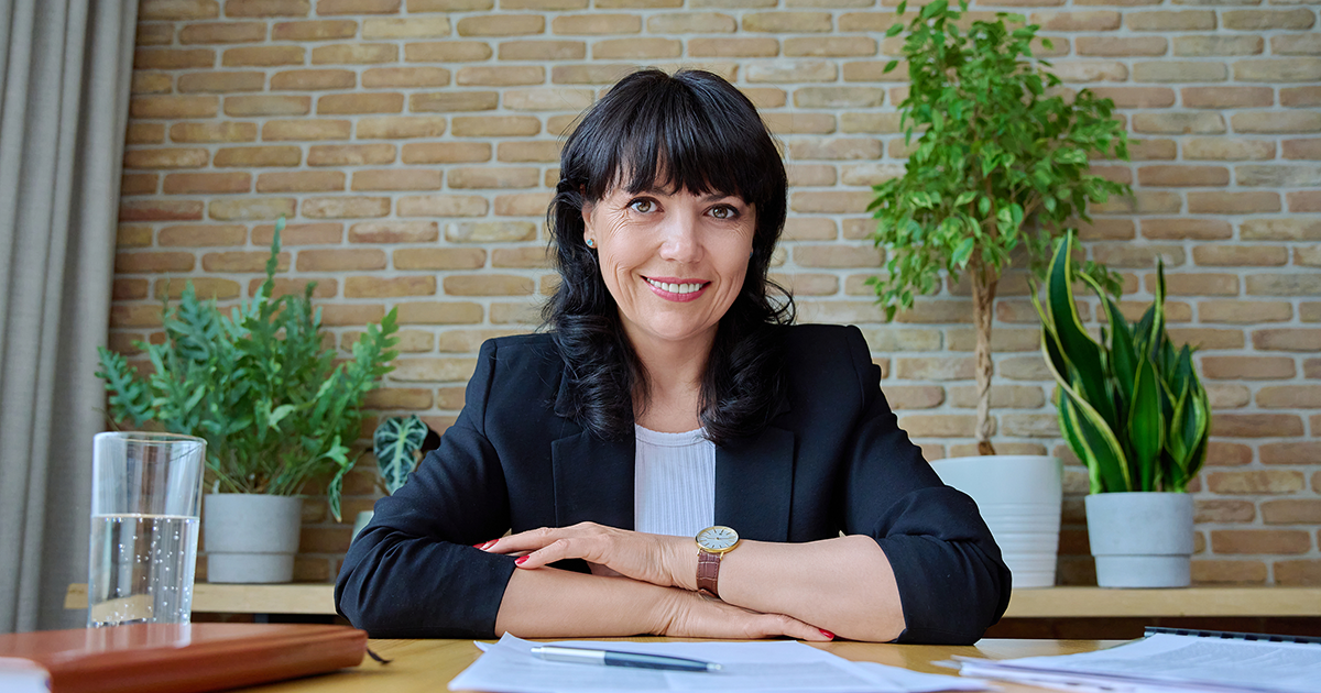 Businesswoman sitting at conference room table smiling at camera. 