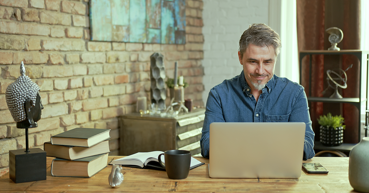 Mature man working on laptop computer in office, thinking, looking busy