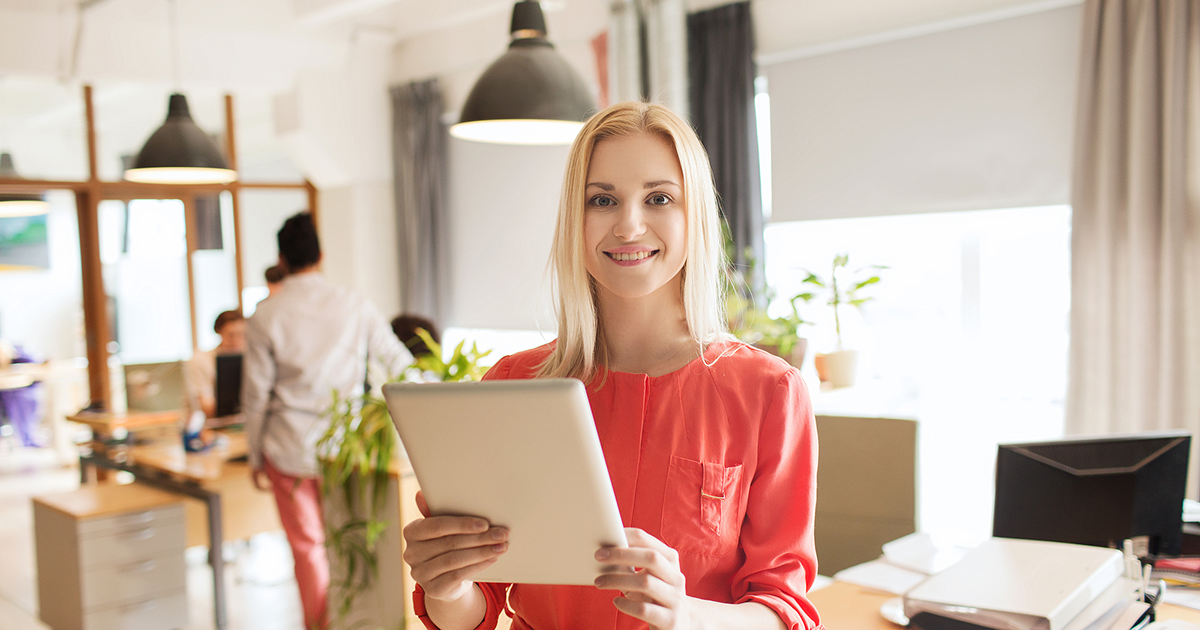 happy businesswoman in office with tablet