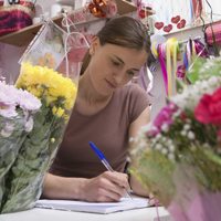woman leaning over papers in flower shop