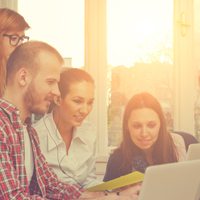 group of men and women huddled around a computer