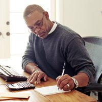 A man sitting at his desk while writing notes.