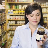 Woman reading a label of a jar.