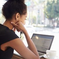 A woman sitting her laptop with a cup of coffee