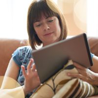 A woman on her couch using her tablet device