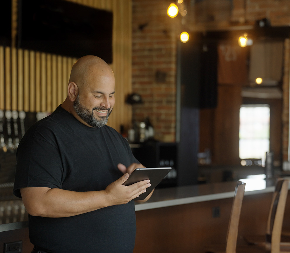 Man working in a restaurant smiling and holding a tablet
